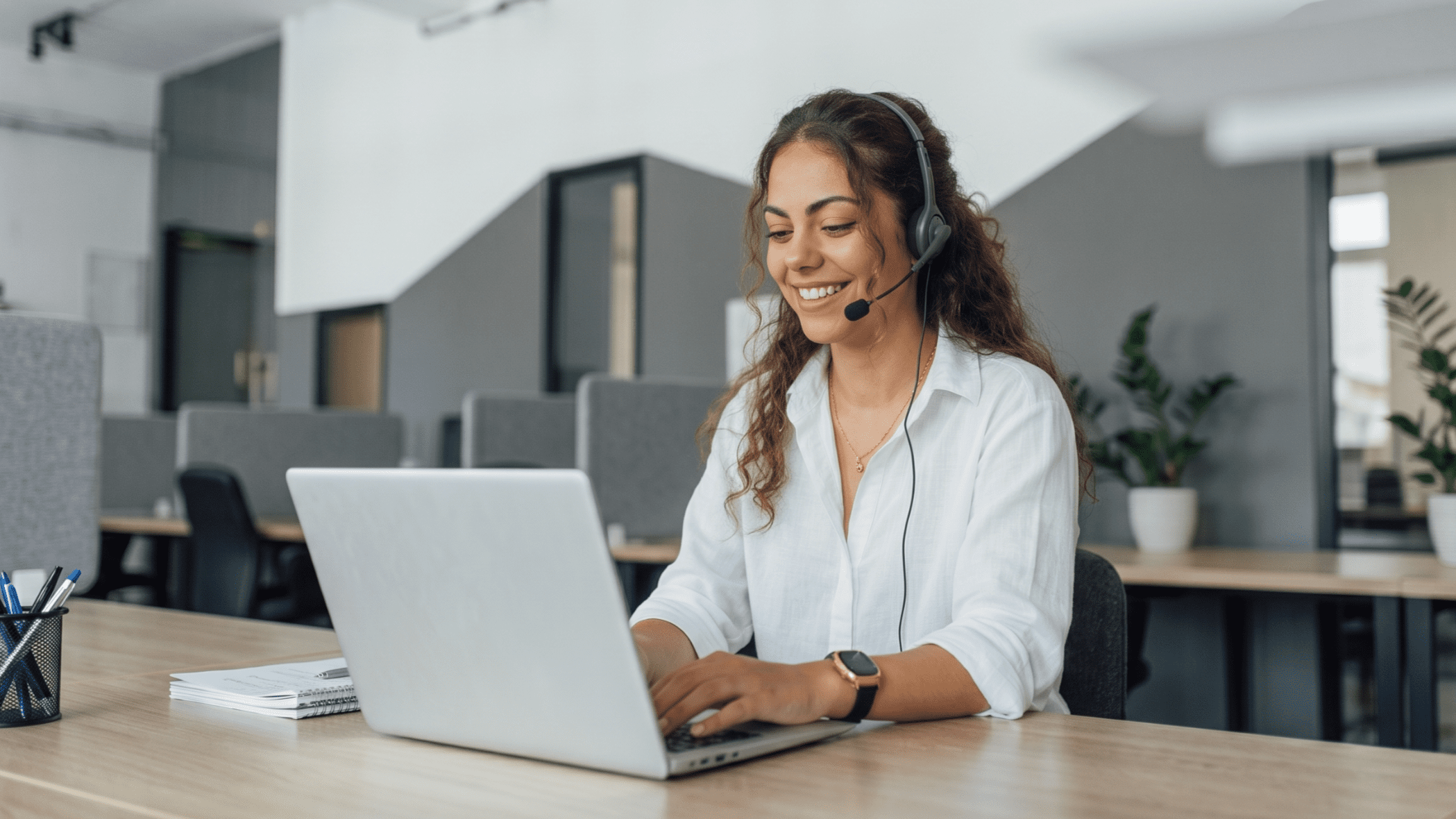 latina remote service coordinator smiling while working on a laptop with a headset on
